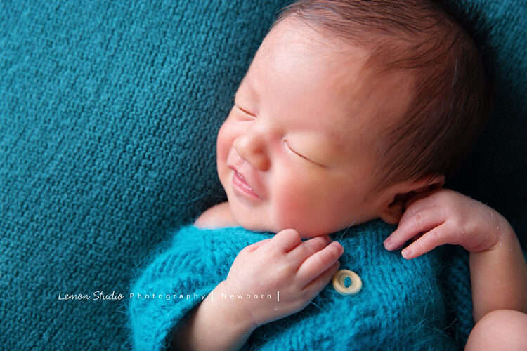 這張相片寶寶包在藍色的布裡，在睡夢中甜甜的笑，好可愛！