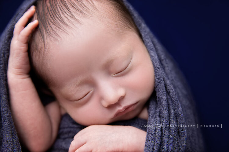 Eva媽麻寶寶的彌月卡拍照，這張寶寶被紫色的布包住，寶寶的手摸摸頭好可愛啊！