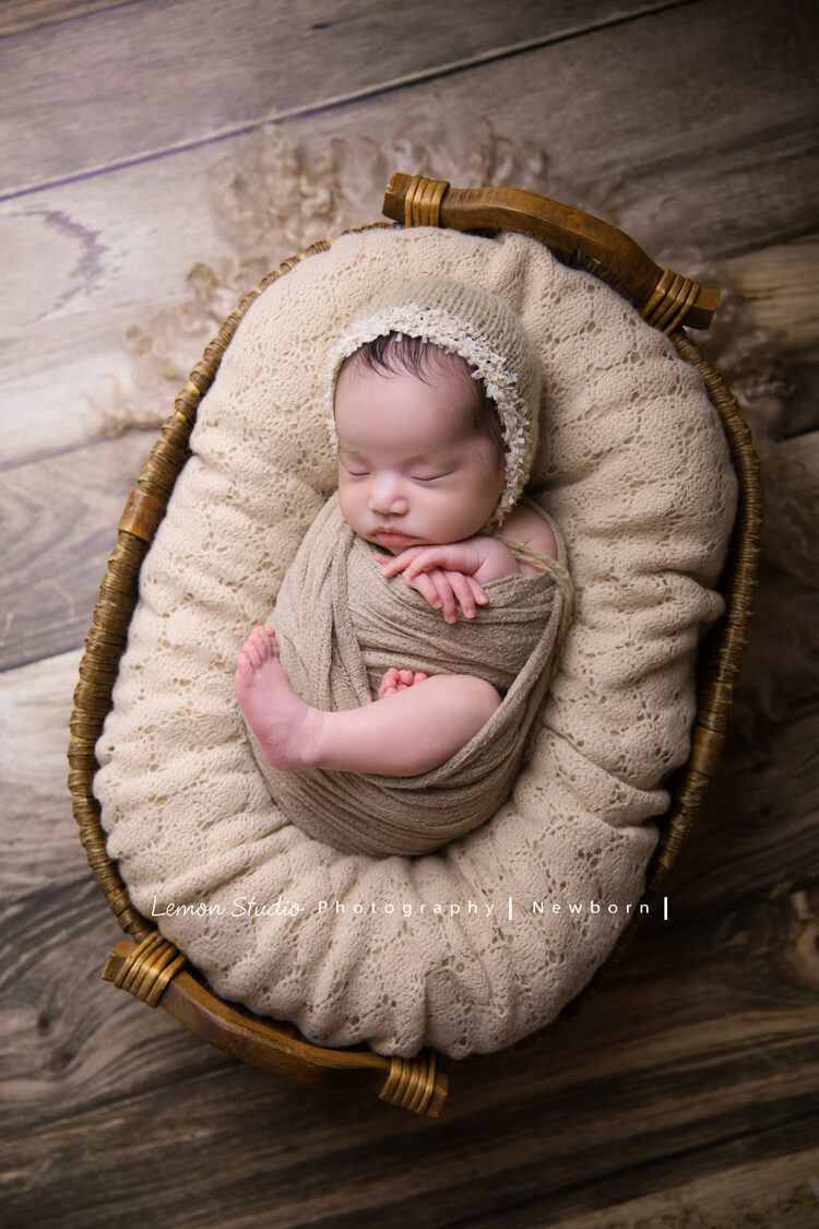 這張相片裡，寶寶包在布裡，躺在籐籃裡，手手腳丫也好可愛，好美好有藝術價值啊