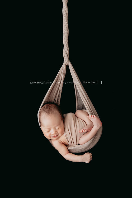 隨手分享新生兒攝影的一張相片，這張相片寶寶包掛在布裡且寶寶在睡夢中微笑，非常經典的一張相片啊！