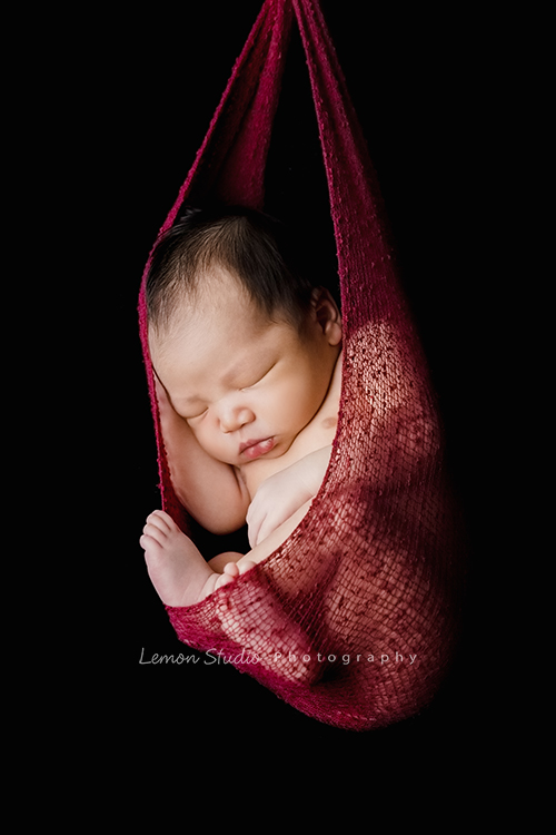 婕綝媽麻的三寶來拍新生兒寫真，這張是三寶掛在紅色的布裡的相片！