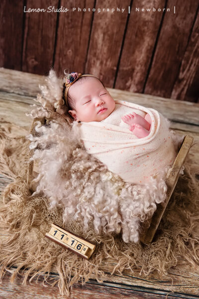Vivien媽麻三寶出生不久來拍新生兒寫真&家庭攝影,這張是寶寶的寫真照,寶寶包在布裡,躺在毛毯上,旁邊的木頭道具顯示寶寶的生日,這張放在彌月卡上超適合!