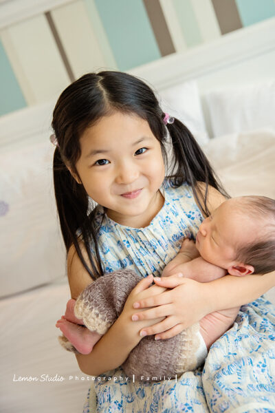 野村師傅一家來拍新生兒攝影,這張是姊姊抱著小弟,姊姊的表情既興奮又滿足開心!