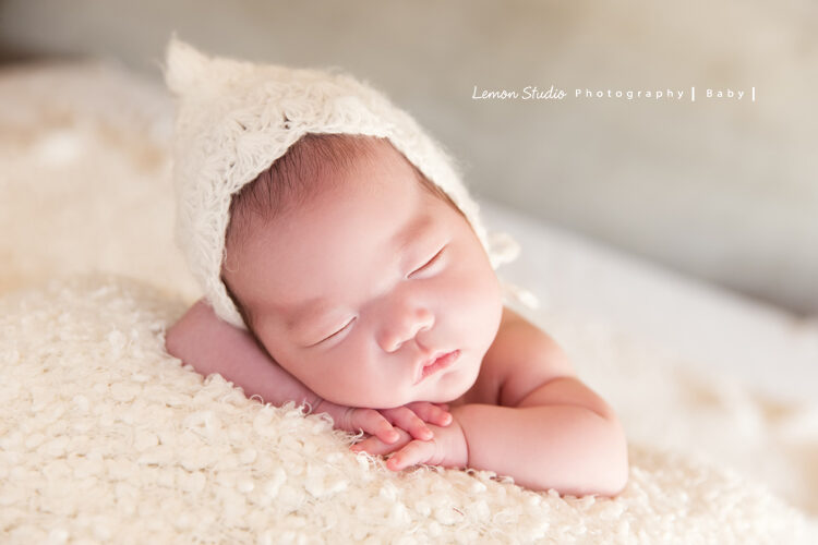 台南小小John一家的新生兒攝影系列相片，小小的John帶著白色頭套趴在手上睡著的樣子好可愛