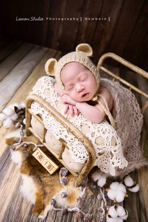 曉文媽麻一家來拍新生兒寫真，這張寶寶趴睡在小床裡，旁邊的木頭日曆標示出寶寶的生日，好適合當彌月卡相片的一張寶寶照！