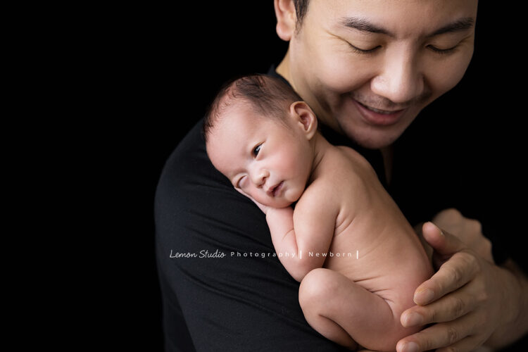 彥君媽麻一家來拍新生兒攝影，這張爸拔抱著寶寶，寶寶已經逐漸醒來睜開一隻眼，好可愛啊！