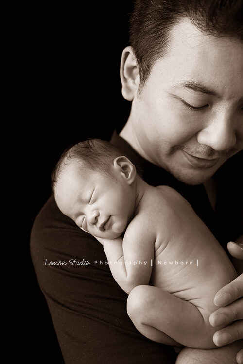 彥君媽麻一家來拍新生兒攝影，這張爸拔抱著寶寶，寶寶在睡夢中微笑！