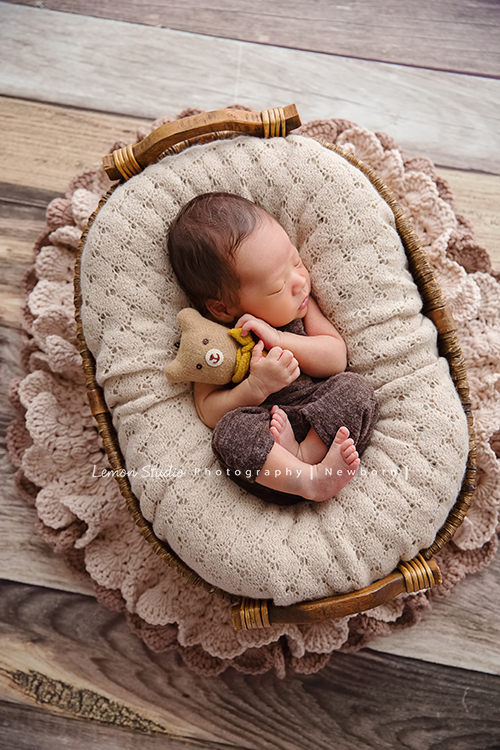 男寶寶乙緁出生13天大時的系列相片，這張寶寶抱著小熊躺在籐籃裡，寶寶的頭髮好順啊！