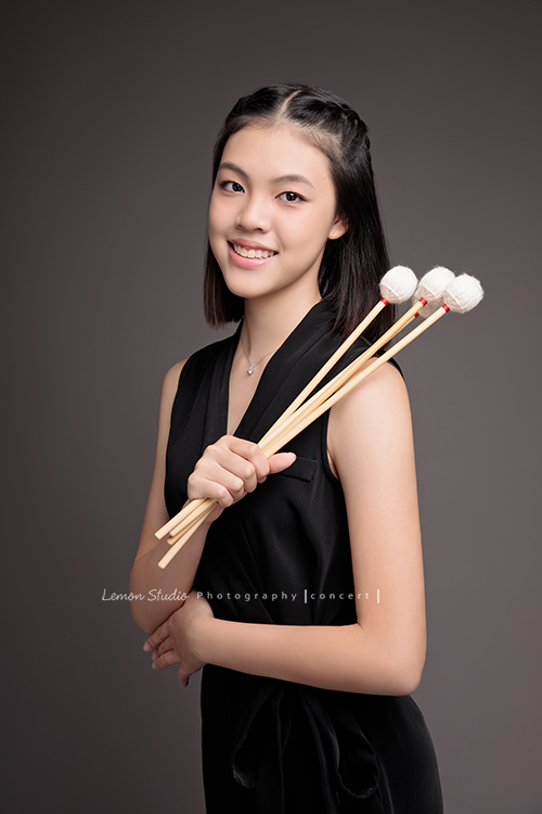 珈瑄學的樂器是馬林巴木琴，這天帶著琴棒來拍照！這張是珈瑄手拿琴棒看著鏡頭微笑的相片，珈瑄帶著自信沈穩的氣質！