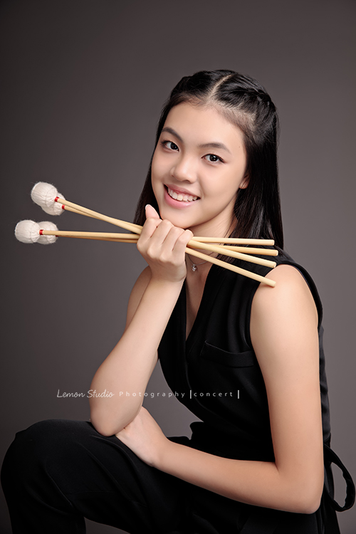 珈瑄學的樂器是馬林巴木琴，這天帶著琴棒來拍照！這張是珈瑄手拿琴棒對著鏡頭笑的相片，珈瑄笑起來很美！