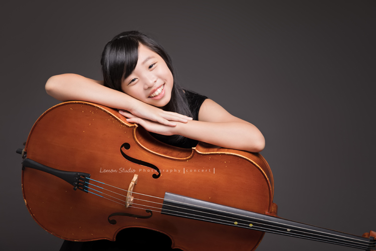 家茵是學校弦樂團的一員，這天和團員們為了即將來到的音樂會一起來拍照！穿著一襲黑色洋裝的家茵與她的大提琴一起拍照！這張是家茵趴在大提琴，家茵的笑容很甜美！