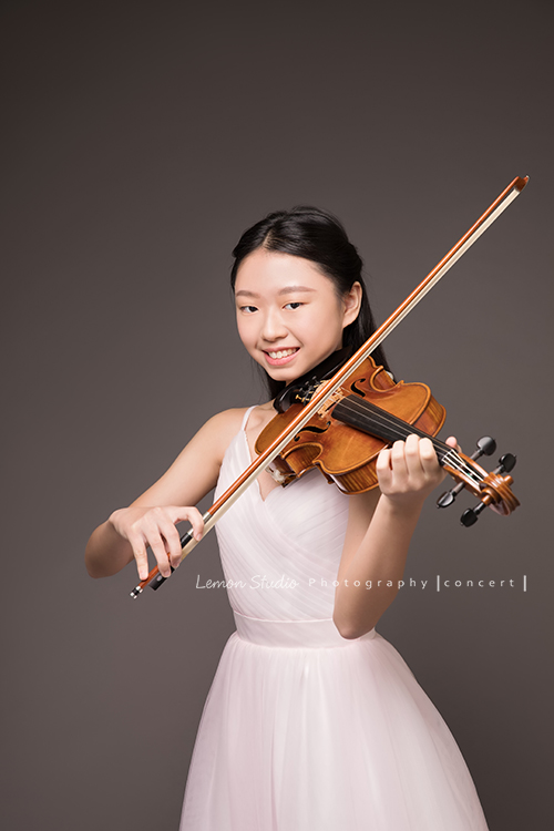 Cindy是學校弦樂團的一員，這天和團員們為了即將來到的音樂會一起來拍照！Cindy穿著一襲白色的禮服很有氣質啊！這張是Cindy在拉提琴很有自信的模樣！
