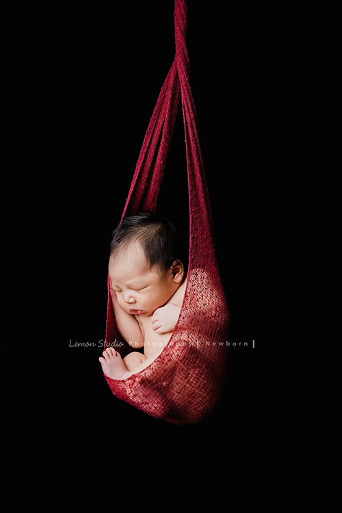 婕綝媽麻的三寶來拍新生兒寫真，這張是三寶吊掛在紅色的布裡的相片！