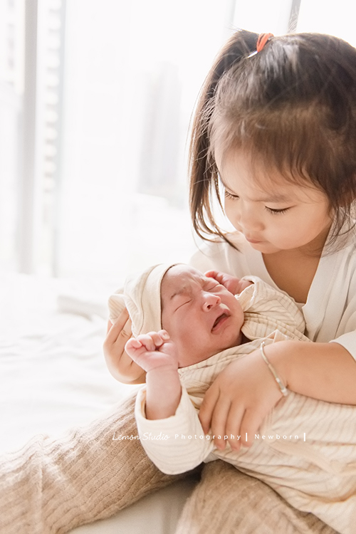 三歲的沐芯當姊姊了好開心啊，這次是拍弟弟的新生兒攝影，承錇媽麻在生產前與黎爸溝通，不用新生兒的可愛道具，希望自然感覺的拍攝，這張是可愛的小姊姊很認真地抱著看著正在哭的弟弟的合照！