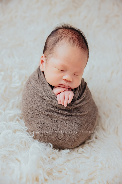 Ida媽麻的二寶男寶寶的新生兒寫真照，繼上次姊姊寶寶時來拍照後，弟弟來報到了！黎爸拍的新生兒寶寶照，每張都像藝術品啊！這張是寶寶包裹在布裡好可愛啊！