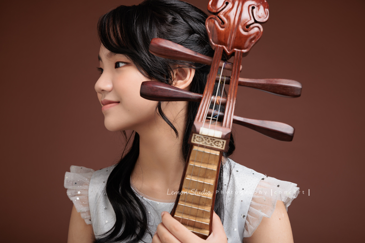 這陣子很多孩子來拍彈奏國樂樂器的音樂會相片，讓我們見識到許多國樂樂器的美好，彈奏柳琴的詠晴是學校國樂團的副首席，這張是詠晴的側面照，好美好有意境的一張相片！