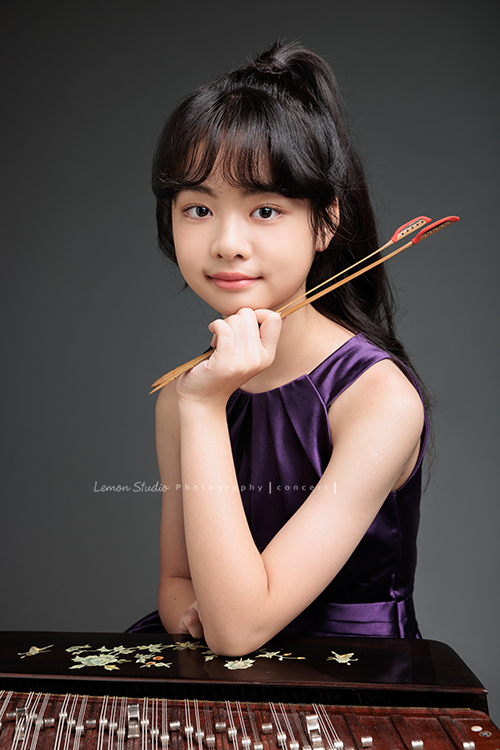 彈奏國樂的揚琴的子晴，這天身穿一襲紫色禮服，將她的揚琴帶到現場拍攝音樂會的相片！這張是子晴的手放在揚琴上對著鏡頭微笑的相片！子晴有雙很美的眼睛！