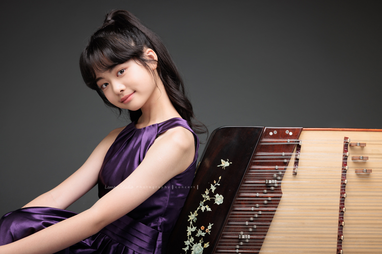 彈奏國樂的揚琴的子晴，這天身穿一襲紫色禮服，將她的揚琴帶到現場拍攝音樂會的相片！這張是子晴的坐靠在揚琴上對著鏡頭微笑的相片！