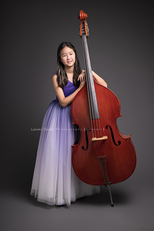 身穿一襲紫色澎裙禮服的亦翎來拍音樂會要用的相片，亦翎好美啊！這張是亦翎扶著大提琴對著鏡頭笑的全身的相片！